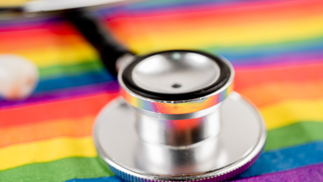 A close-up photo of a stethoscope on a rainbow flag.